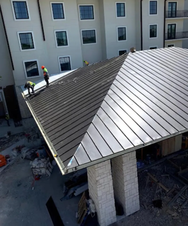 Crew installing standing seam metal roof panels on a commercial project in McFarland